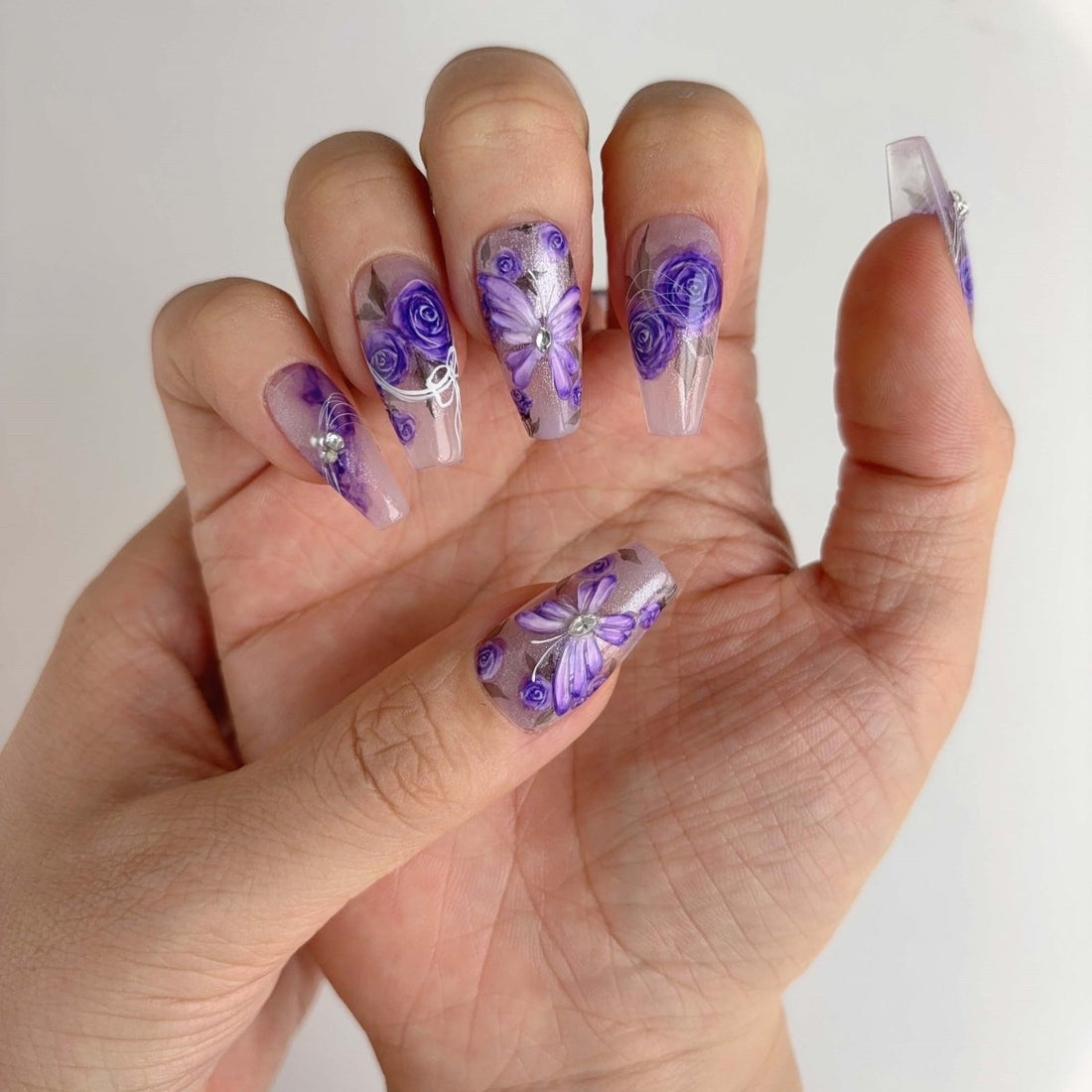 Elegant hand-painted lavender rose nails with 3D butterflies and sparkles in coffin shape