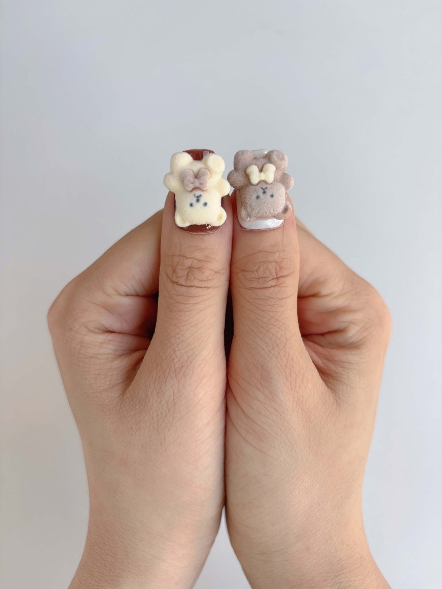 Close-up of teddy bear charm and pearl heart design on medium coffin nails