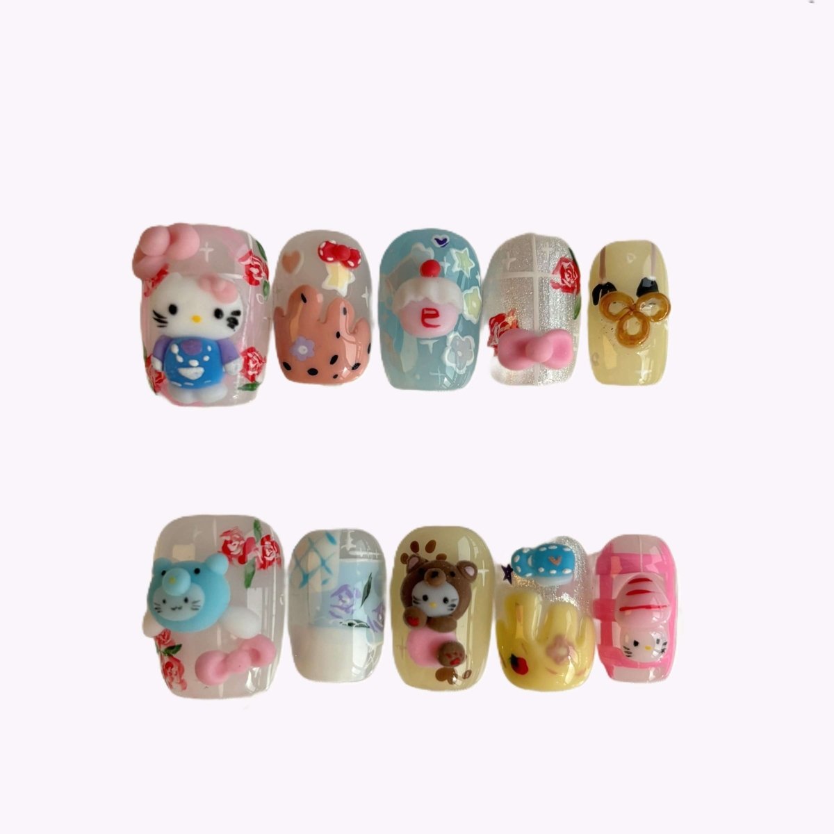 Flat lay of Hello Cutie Carnival 3D press-on nails with Hello Kitty, bears, bunnies, and pastel charms in a clear case on lace background