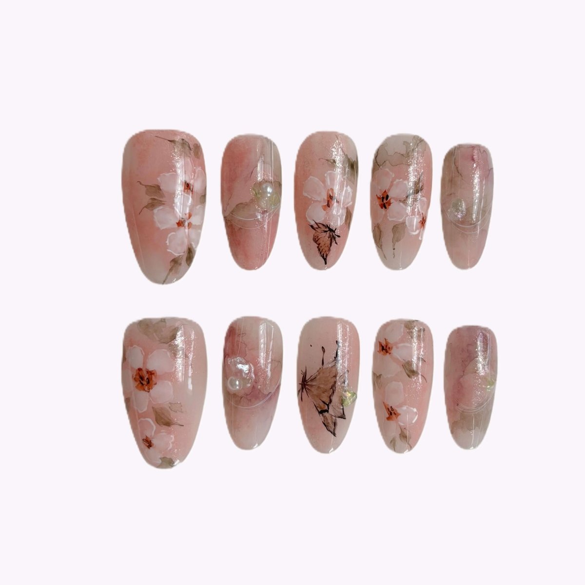 Close-up of Sakura Whisper press-on nails with blush pink base and cherry blossom design in storage case