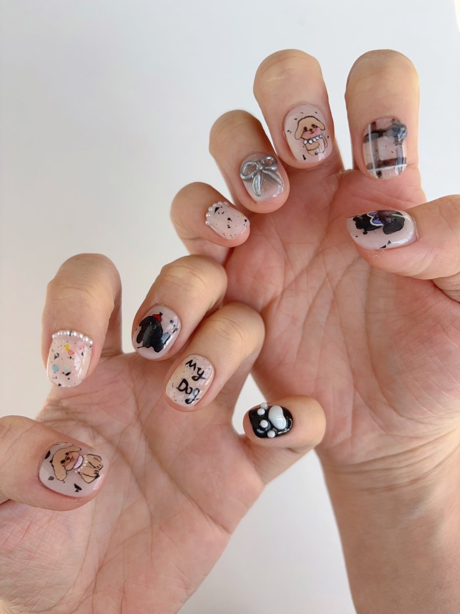 Handmade dog-themed press-on nails featuring pug and black puppy illustrations on nude base