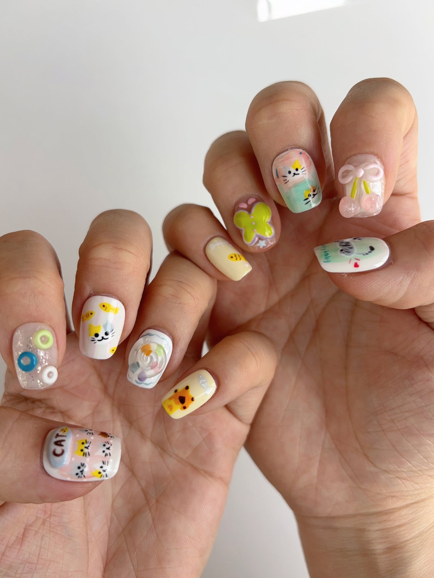 Whimsical cat-themed press-on nails with hand-painted kittens, 3D cherry bows, and soft pastel colors
