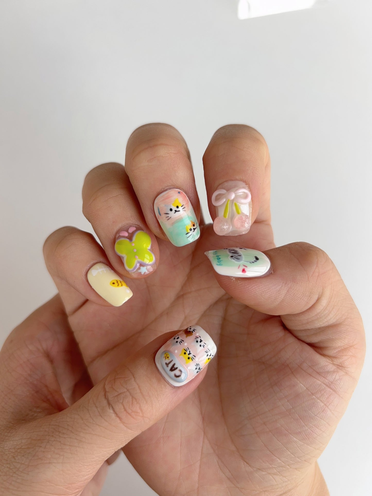 Short square handmade press-on nails with kawaii illustrations, pink blush cheeks, and playful textures