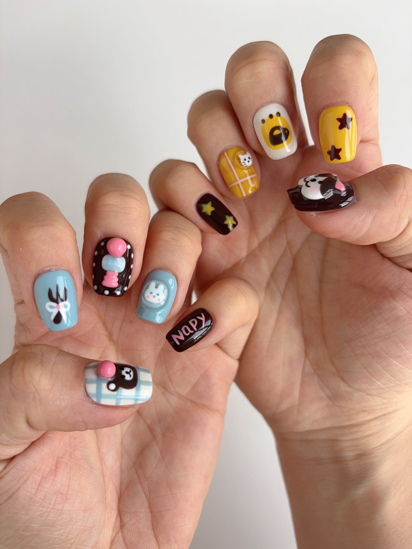 Yellow and white nails with shouting cartoon bear and mini orange cat wrapped in grid pattern