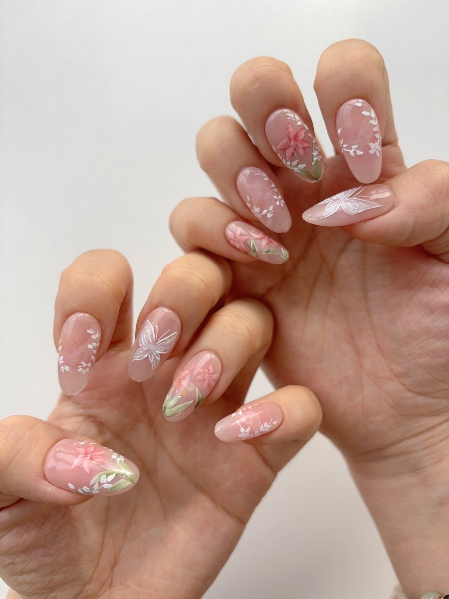 Almond shaped nude nails with coral lily and white flower designs