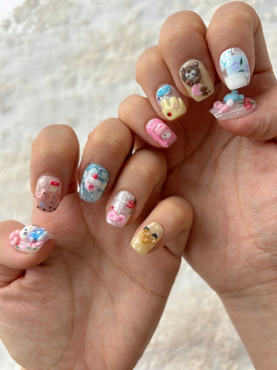 Side angle of press-on nail set with pastel animal characters, glitter, and 3D dessert elements in kawaii style