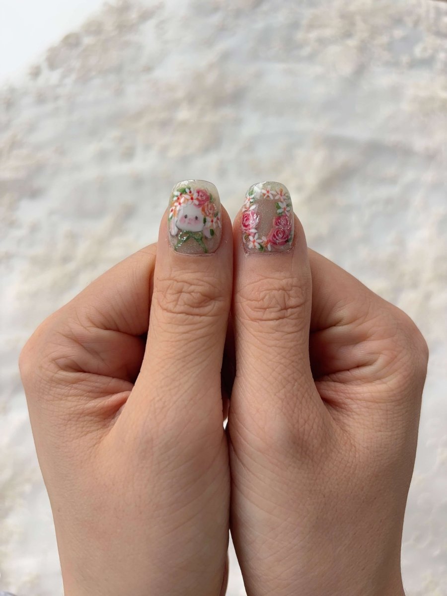Thumbs showing 3D bunny and rose wreath design on iridescent shimmer press-on nails