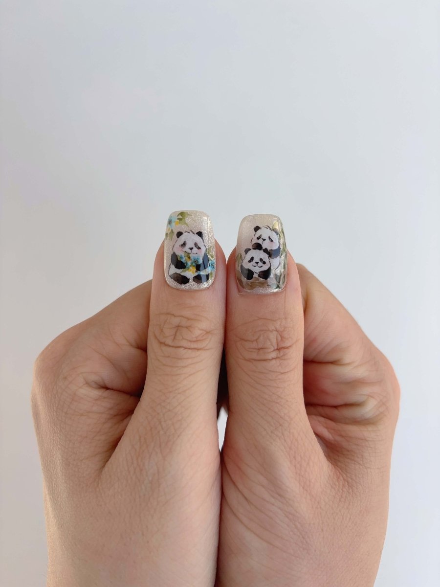 Thumbs with detailed panda designs and yellow blue flowers on press-on nails