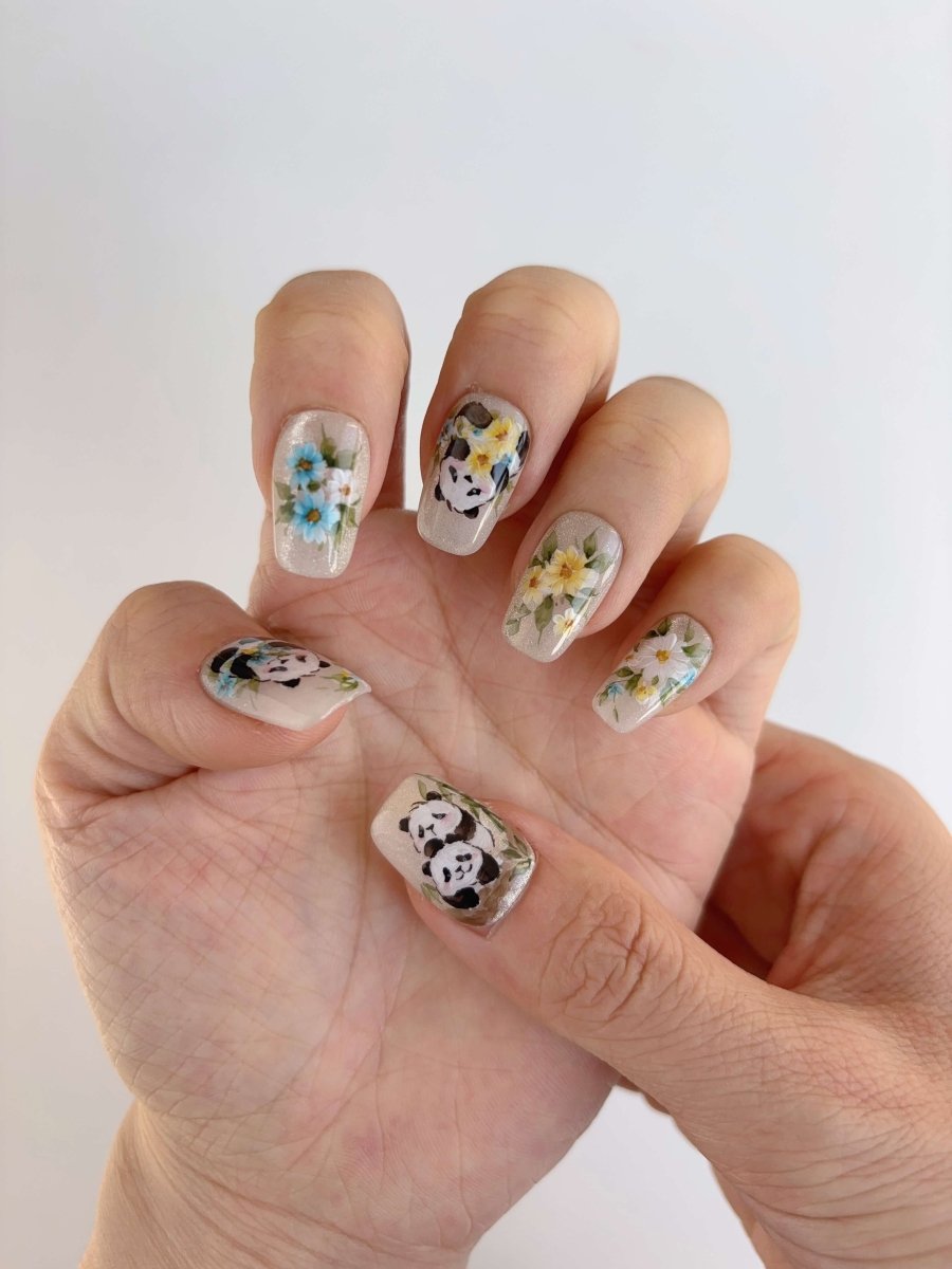Shimmer nude panda nails with floral designs and nature-inspired artwork