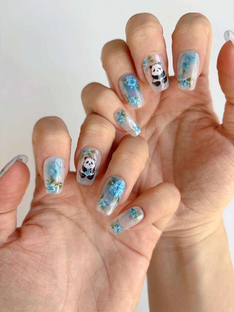Both hands showing floral panda nail art on long square nails