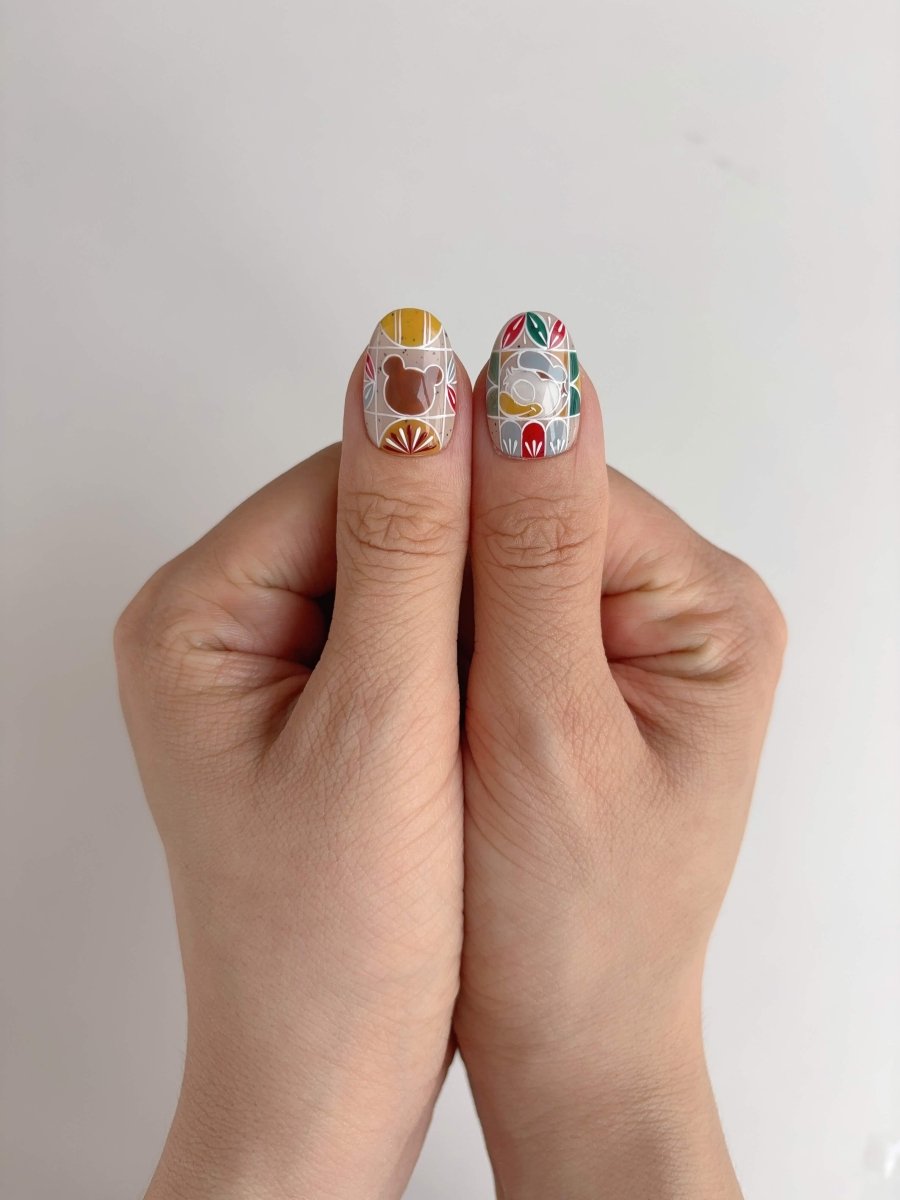 Close-up of thumb nails with bear and bunny silhouettes on colorful cottagecore press-ons