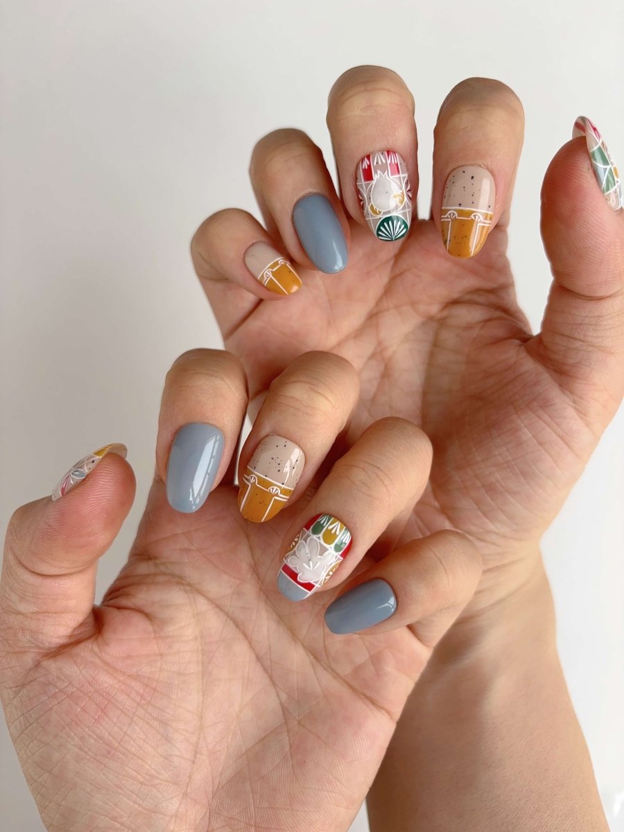 Two hands wearing Forest Folk short oval press-on nails with earth tones and artisan details