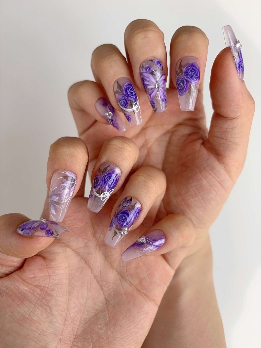 Full set of hands showcasing lavender bloom nails with detailed flower painting and crystals
