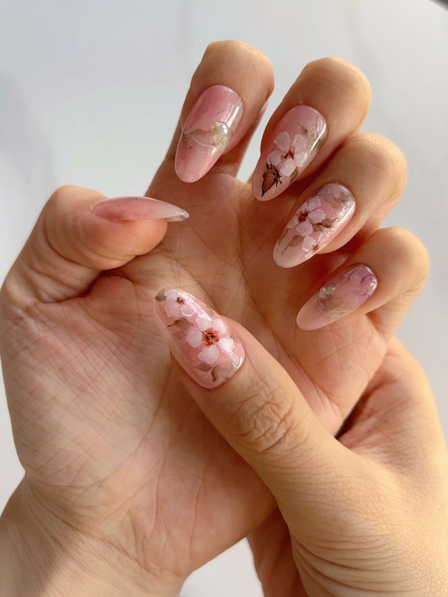 Side angle of hand showing gradient cherry blossom nails and vintage butterfly detail