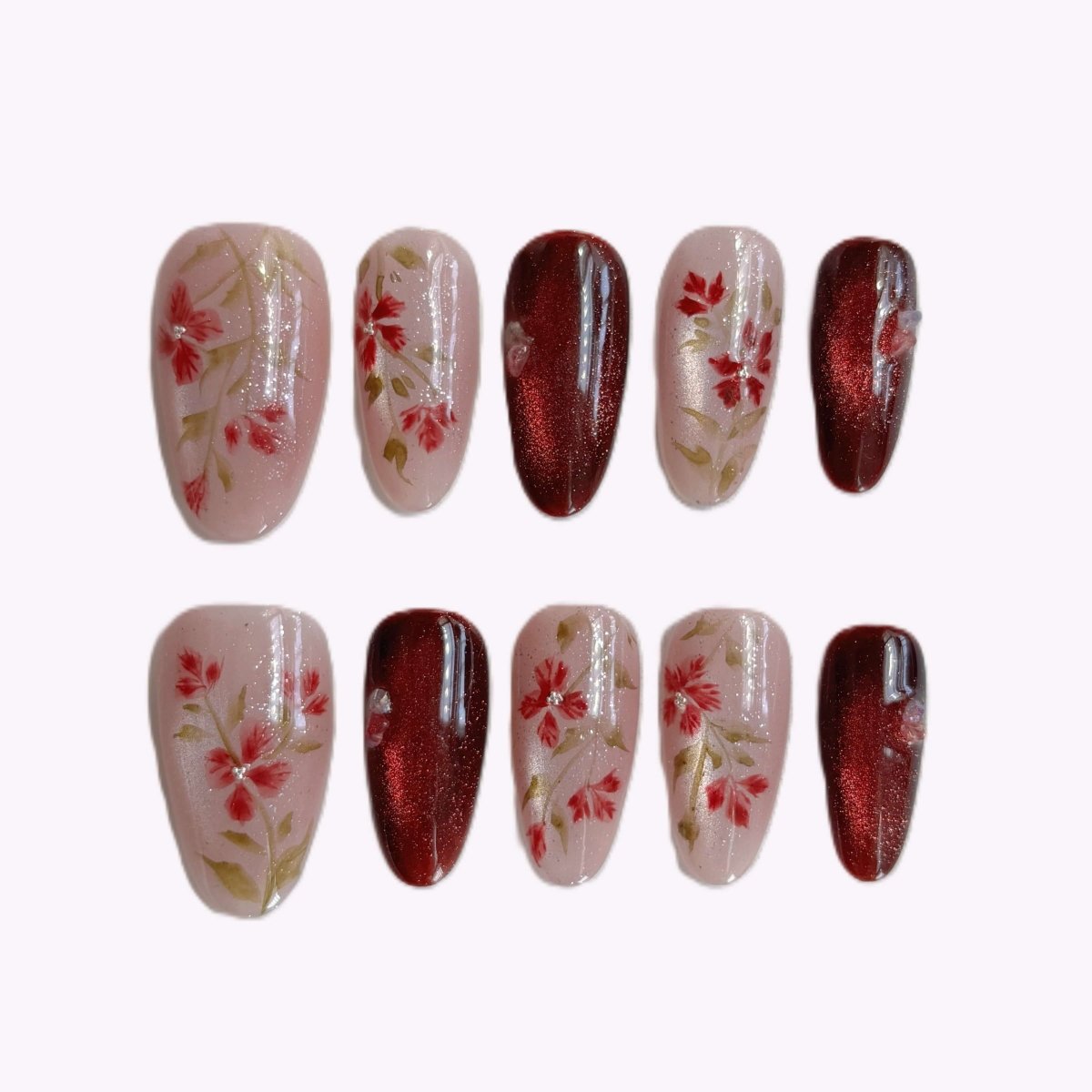 Crimson Bloom press-on nail set featuring burgundy cat eye shimmer and red wildflower accents in case