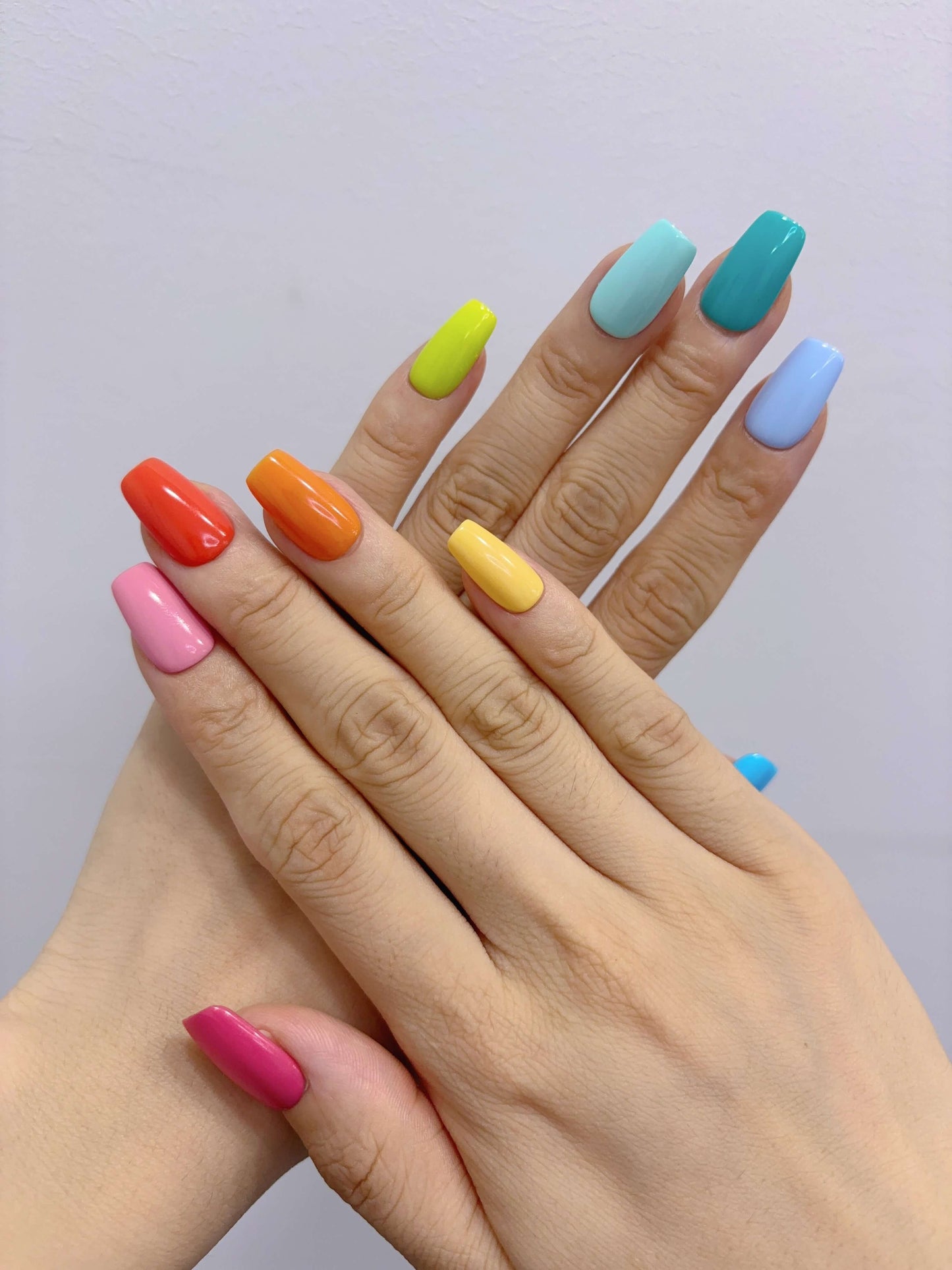 Hands posed to show Technicolor Tips press-on nails in solid bright colours
