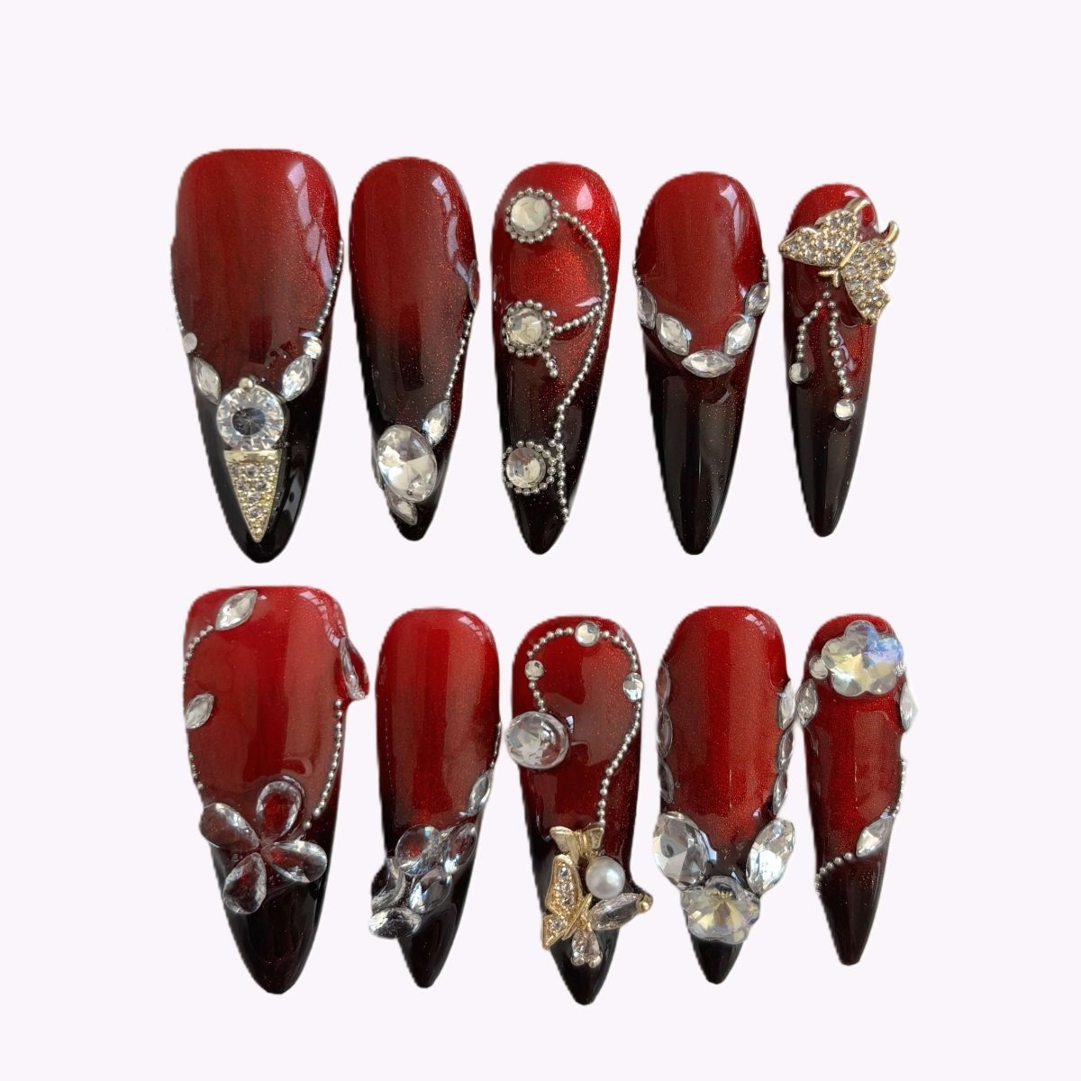 Full nail set in a case featuring red to black ombré stiletto nails with crystals and 3D embellishments