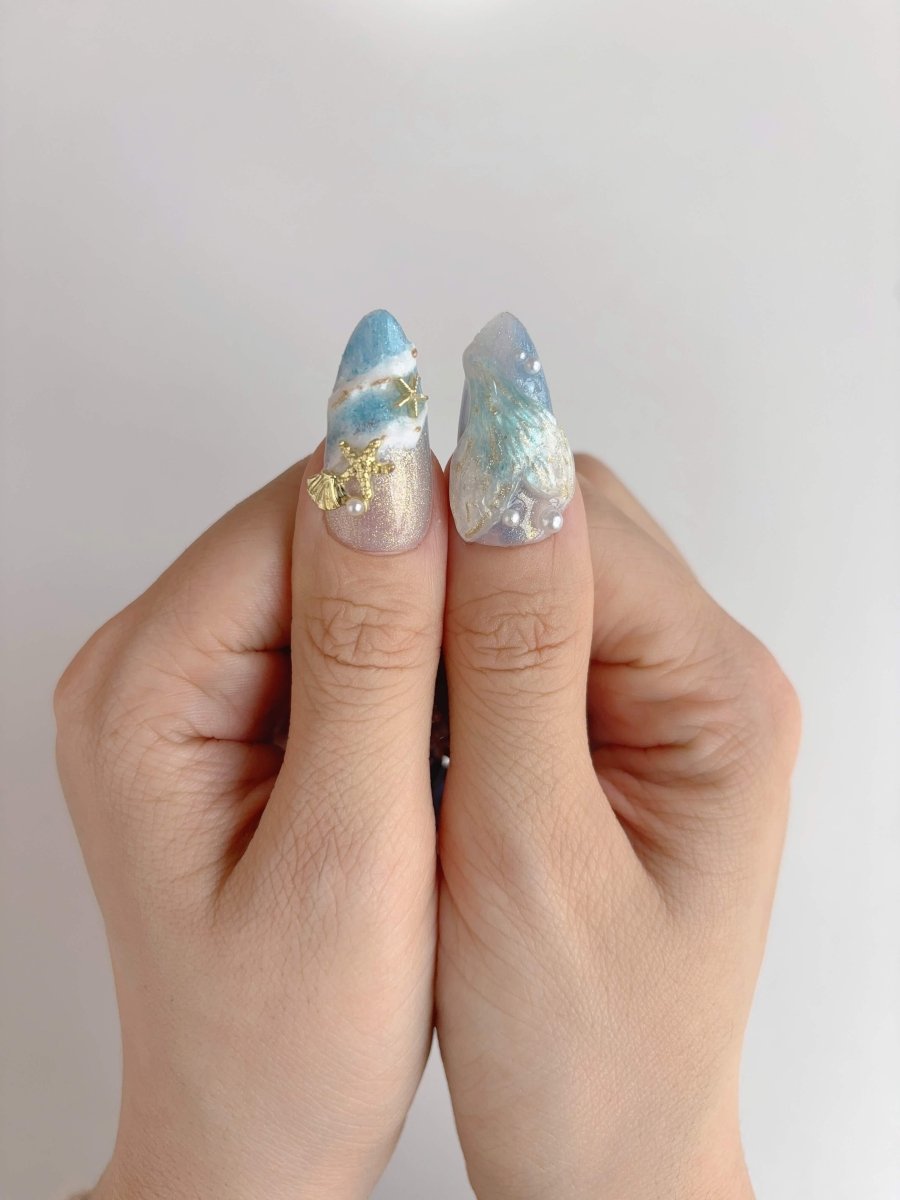 Thumb view of mermaid press-on nails with golden starfish charm and sculpted pearl tail design