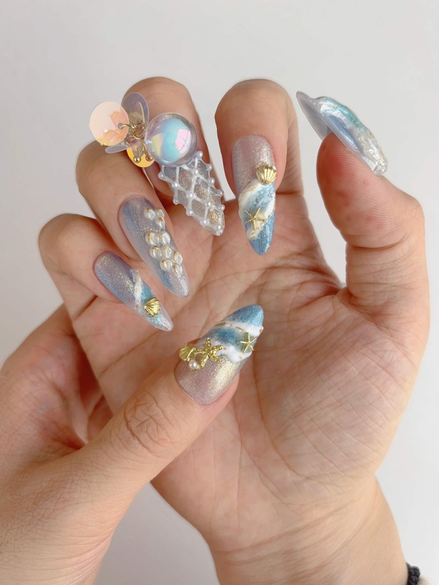 Hand modeling long stiletto mermaid nails with shell details, iridescent pearls and sculpted waves