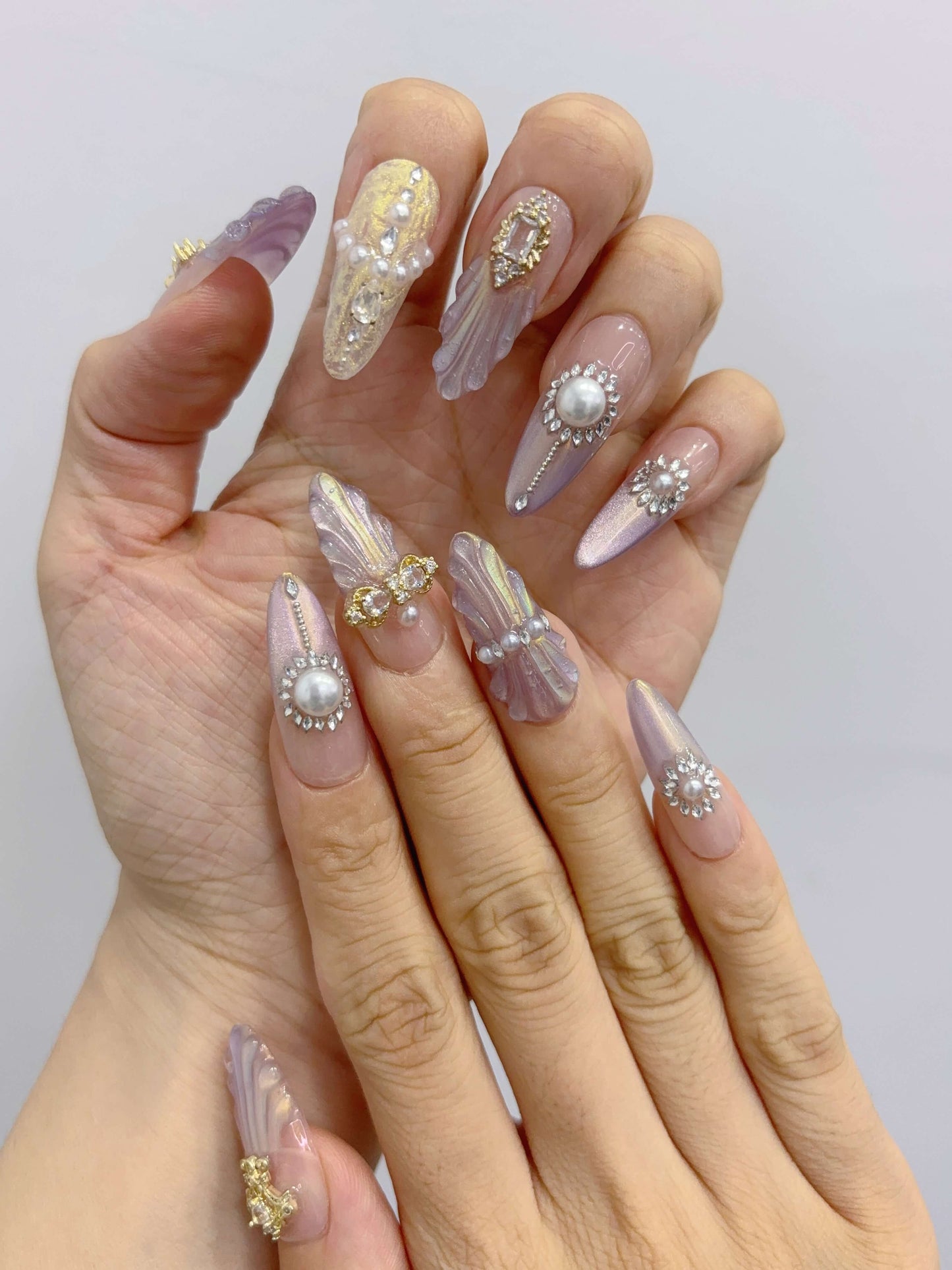 Two hands showing full Royal Shell nail set with iridescent shimmer and 3D detailing