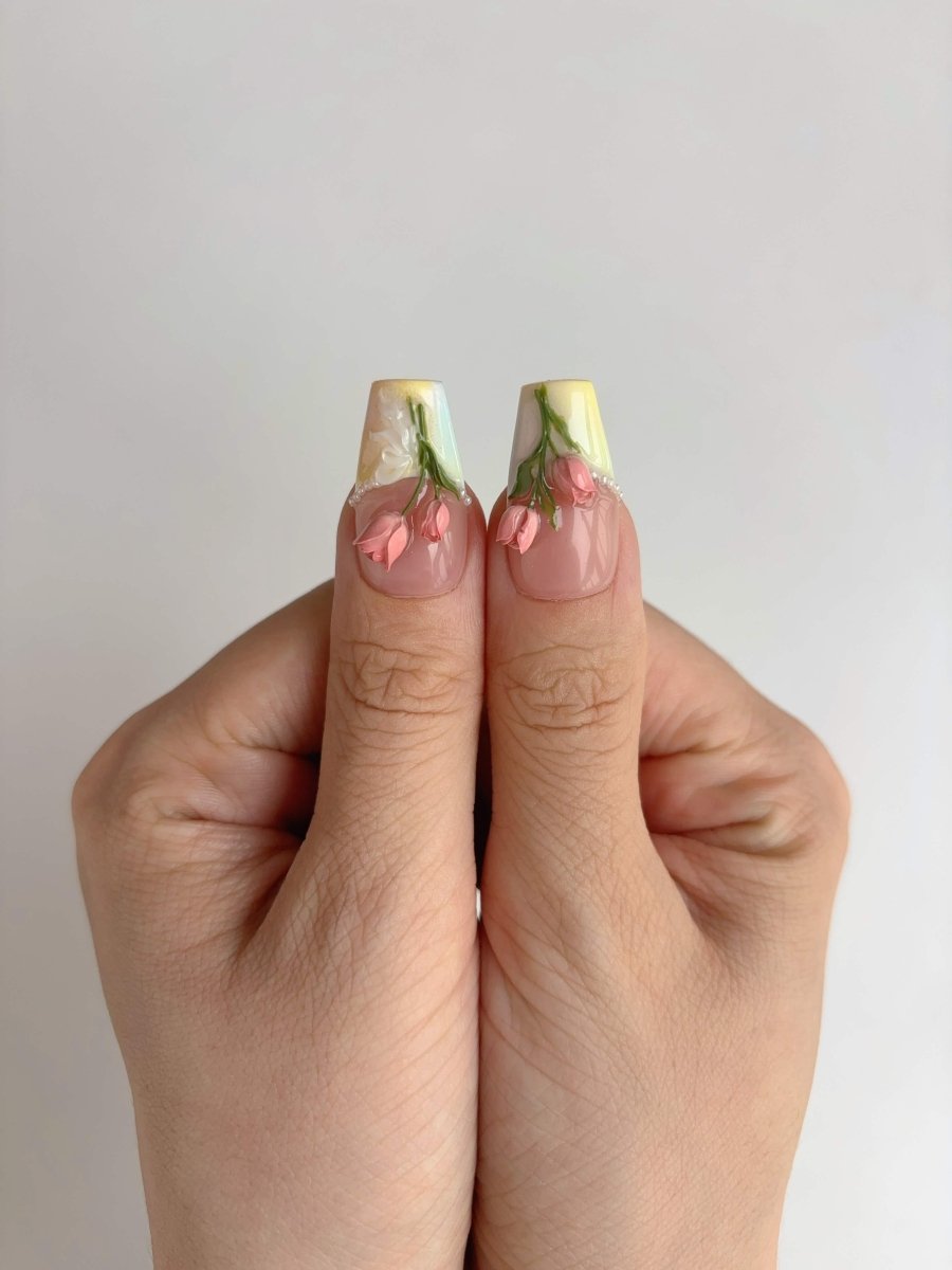 Close-up of thumb nails featuring coral rosebuds on a glossy nude base
