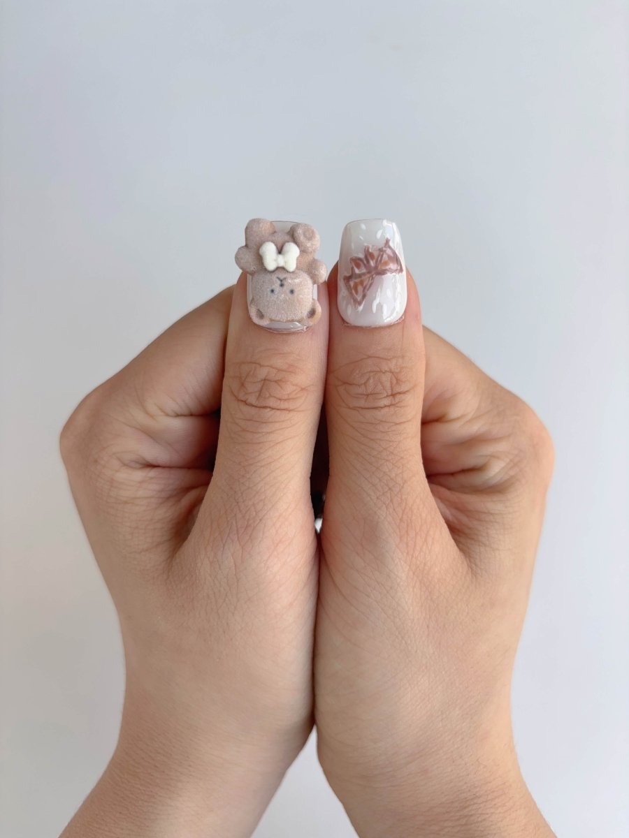 Thumbs showing plush teddy bear nail charm and bow accent press-on nail