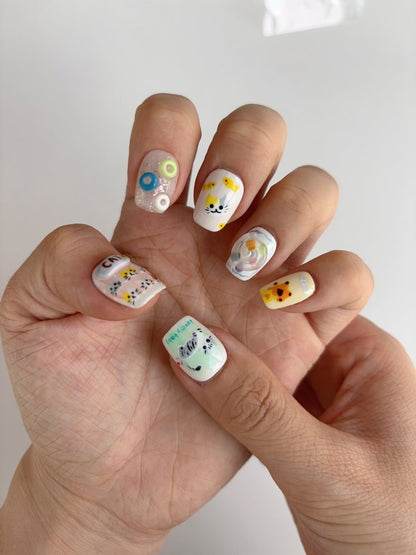 Close-up of 3D cat and candy press-on nails featuring sculpted butterfly, glitter bubbles, and yellow fish accents