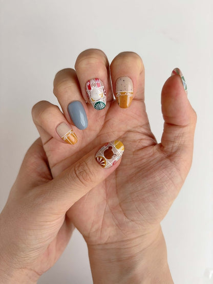 Short oval nails with mustard, sage, and red stained-glass patterns with hand-drawn forest creatures