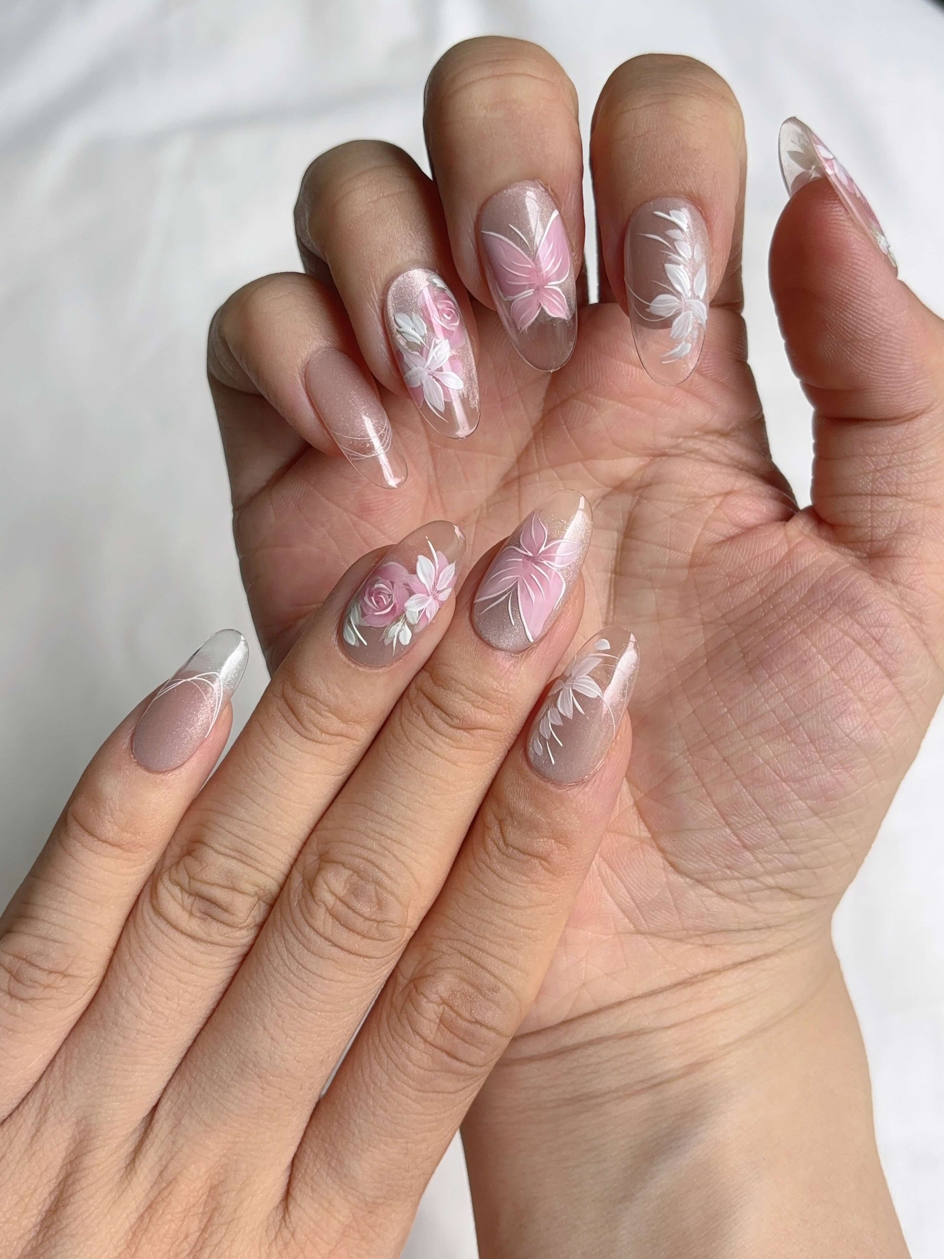 Angled view of Rosé Reverie nails showcasing pink shimmer and painted petals