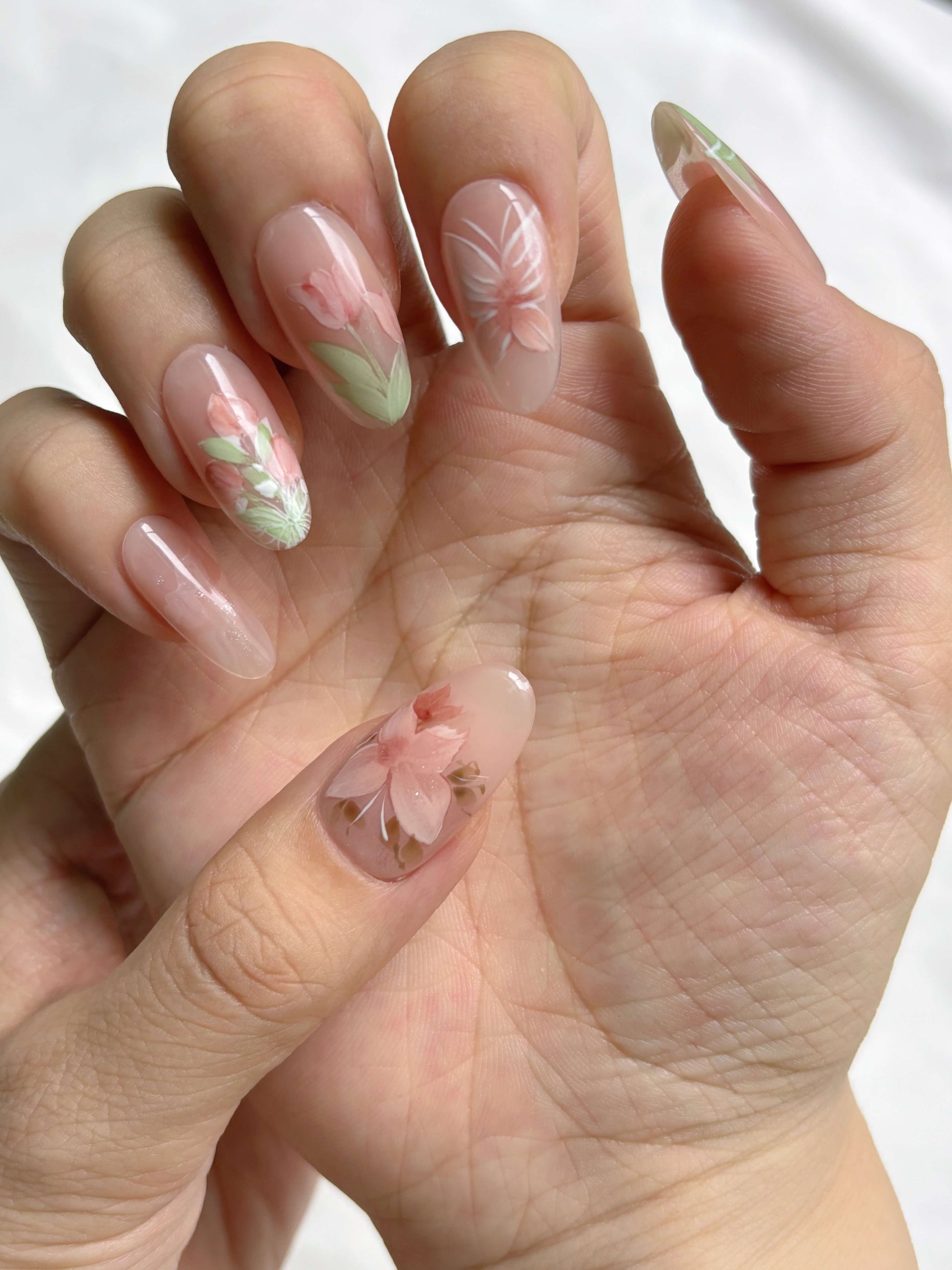 Hand wearing Petal Veil nails featuring delicate petal artworK