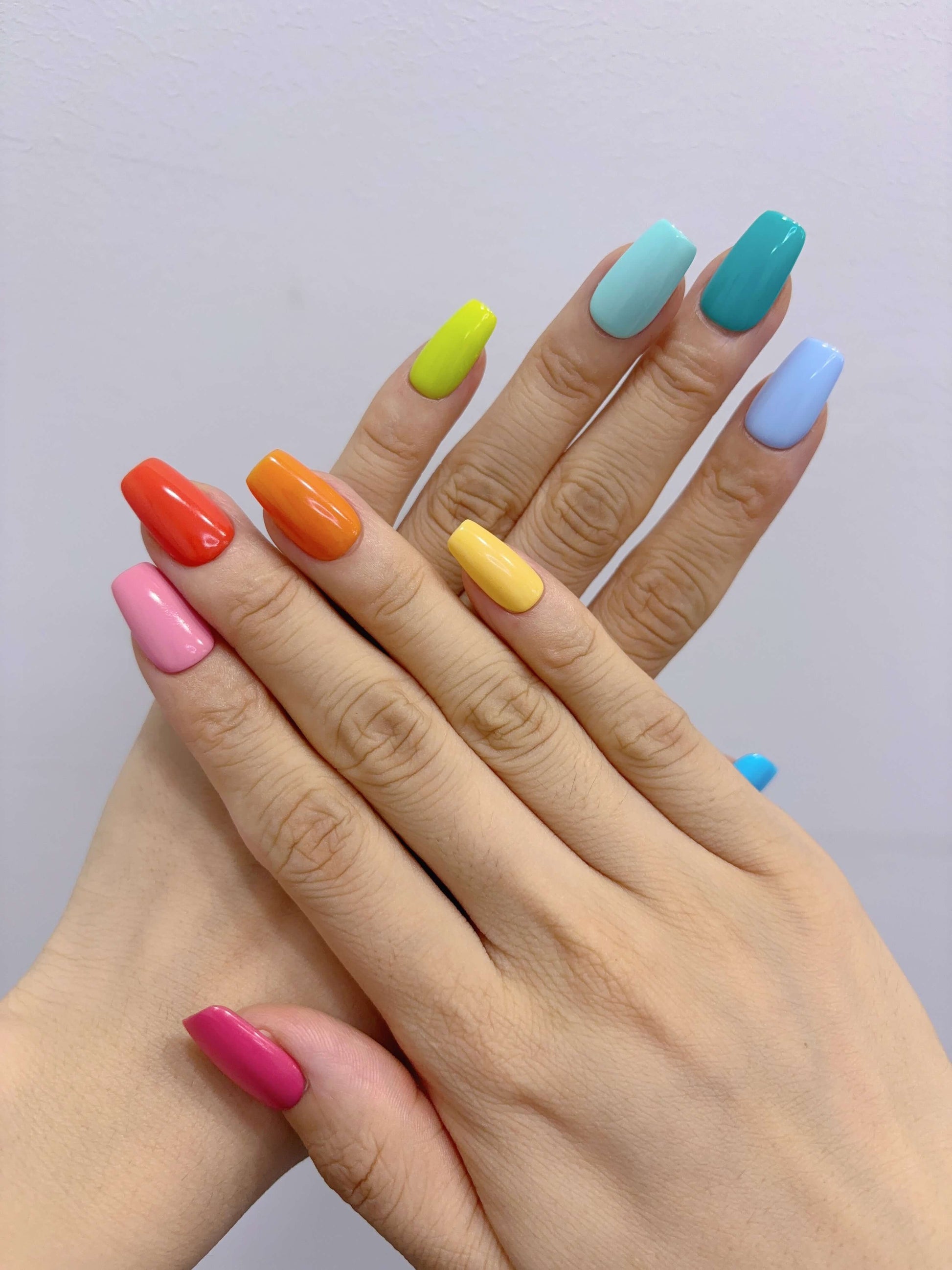 Hands posed to show Technicolor Tips press-on nails in solid bright colours