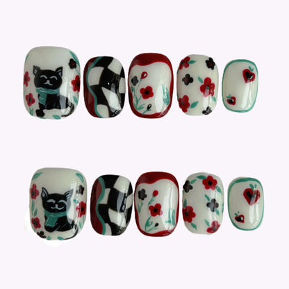 “Lucky Cat Bloom press-on nails flat lay with cat, checkerboard and floral accents