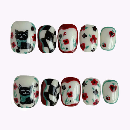 “Lucky Cat Bloom press-on nails flat lay with cat, checkerboard and floral accents