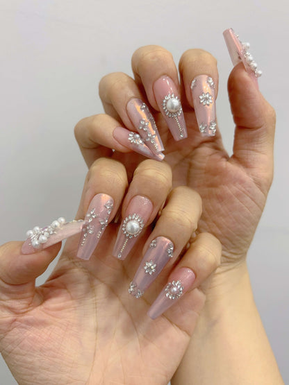 “Two hands showing full Pearl Eclipse nail set with iridescent base and crystal embellishments