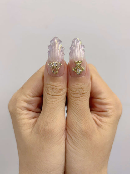 Close-up of thumbs with crown and bow charms on sculpted shell background